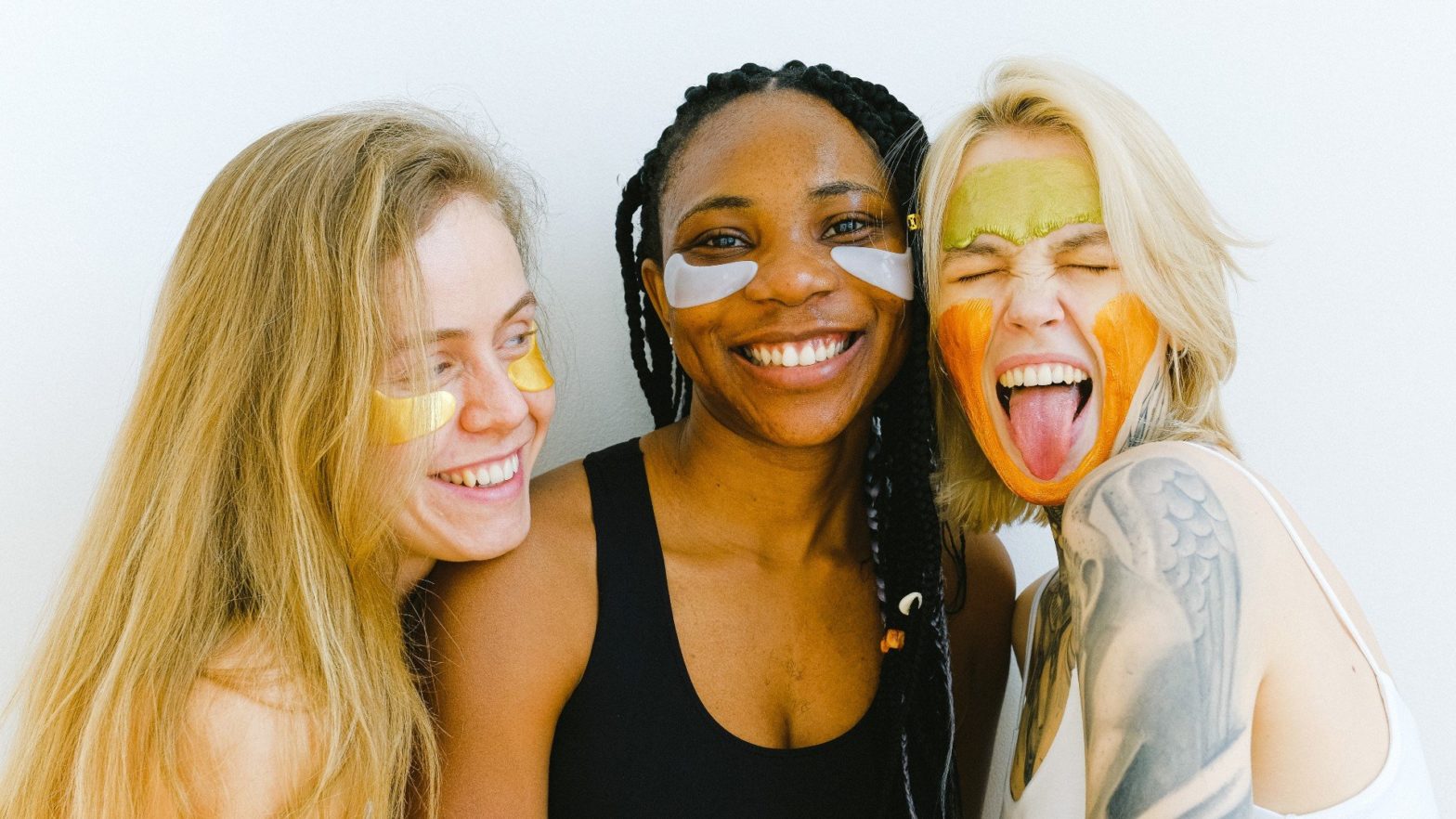3 mulheres sorrindo e com o rosto cheio de base colorida.