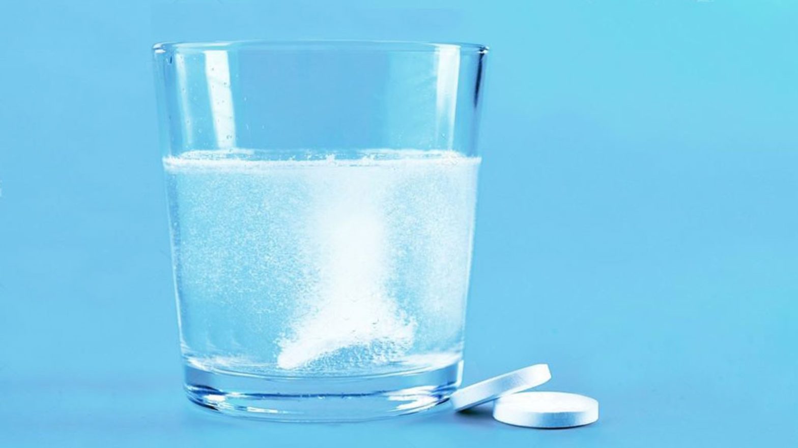 copo de água com dois comprimidos efervescentes ao lado