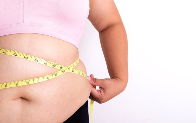 Mulher com obesidade medindo a circunferência abdominal.