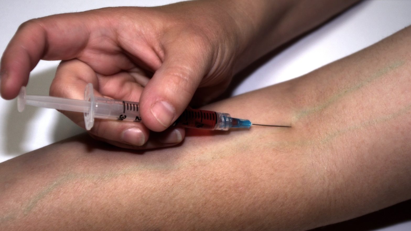 Uma pesoa aplicando a injeção de HCG na veia do braço.