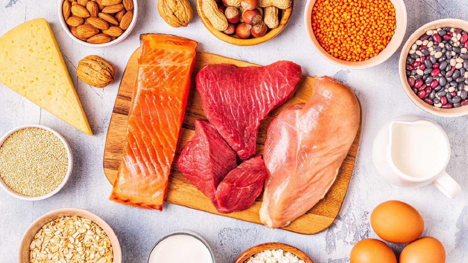 Alimentos ricos em vitamina D como salmão, carne vermelha, laticinios, ovos sobre uma mesa.