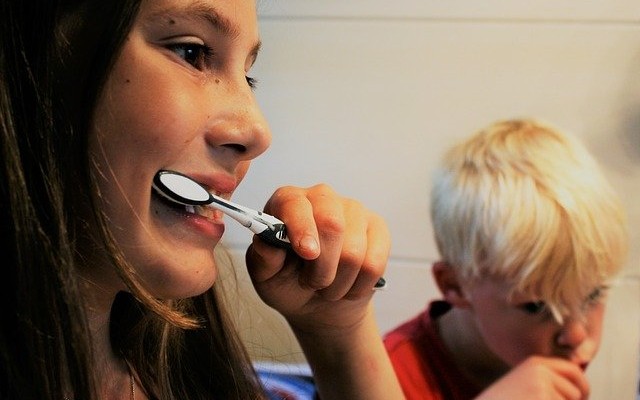 Menina adolescente e menino criança escovando os dentes.