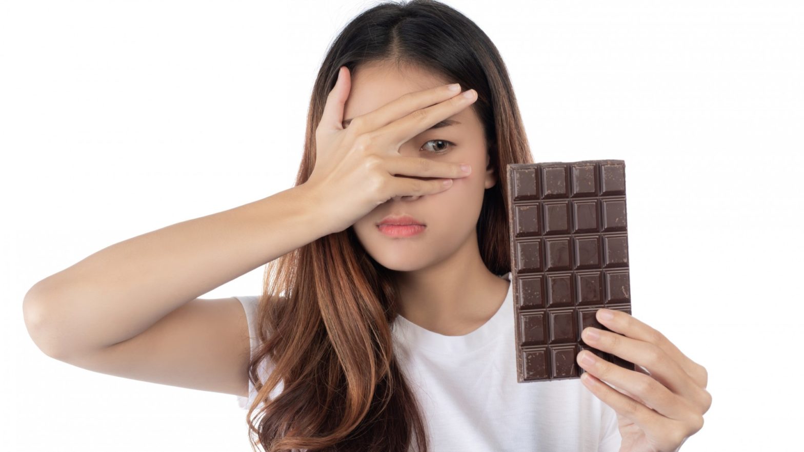 Mulher com semblante desconfiado olhando uma barra de chocolate.